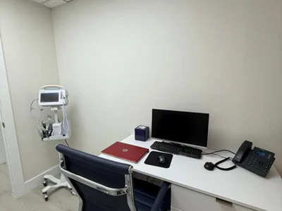 Oficina médica privada con escritorio, silla ejecutiva y equipo médico especializado