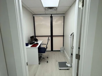 Consultorio médico con báscula digital, escritorio y equipo de diagnóstico moderno