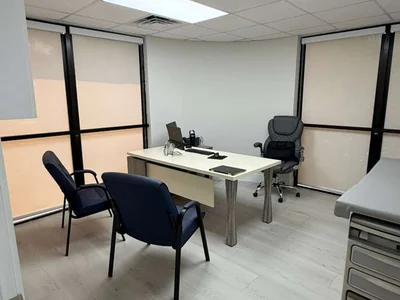 Oficina ejecutiva con ventanas amplias, escritorio moderno y sillas para consultas